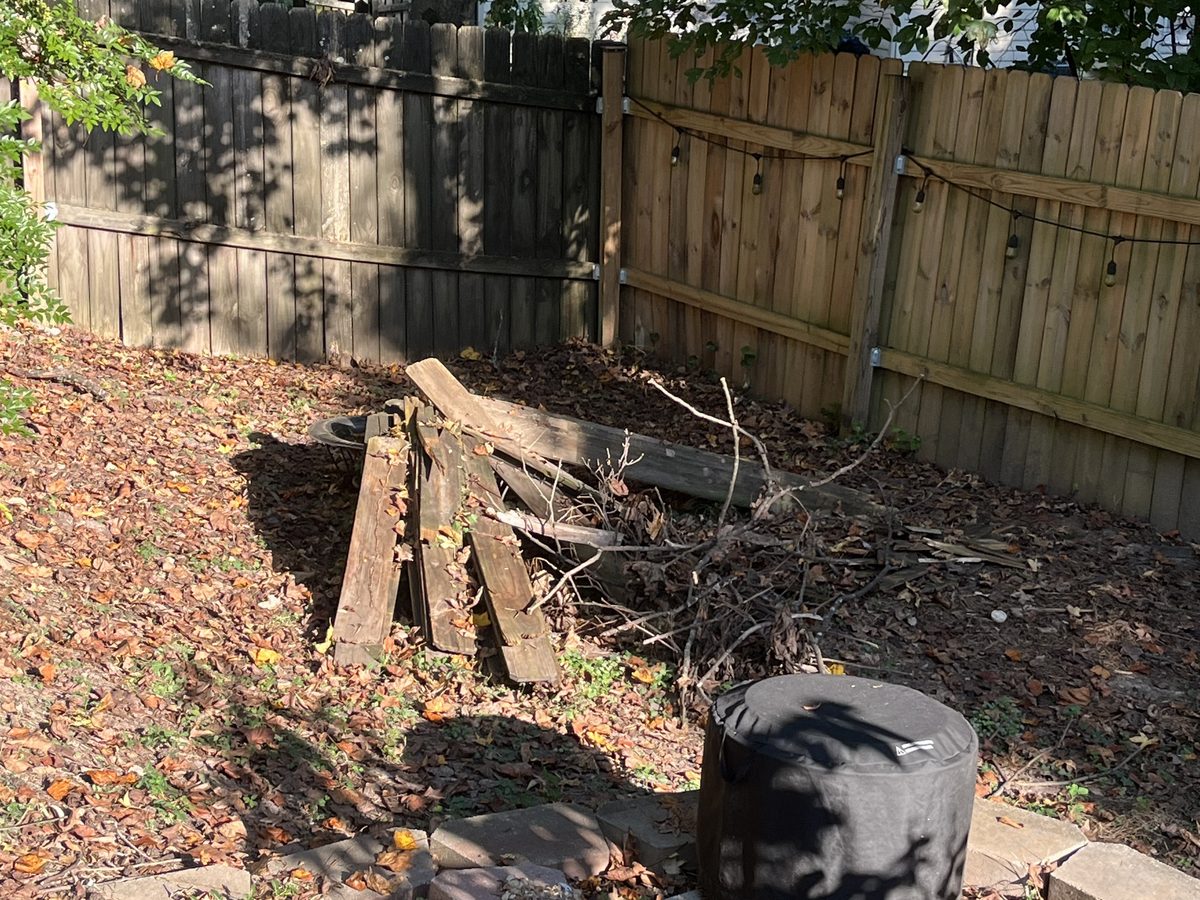 Yard debris piled along a fence line before pickup